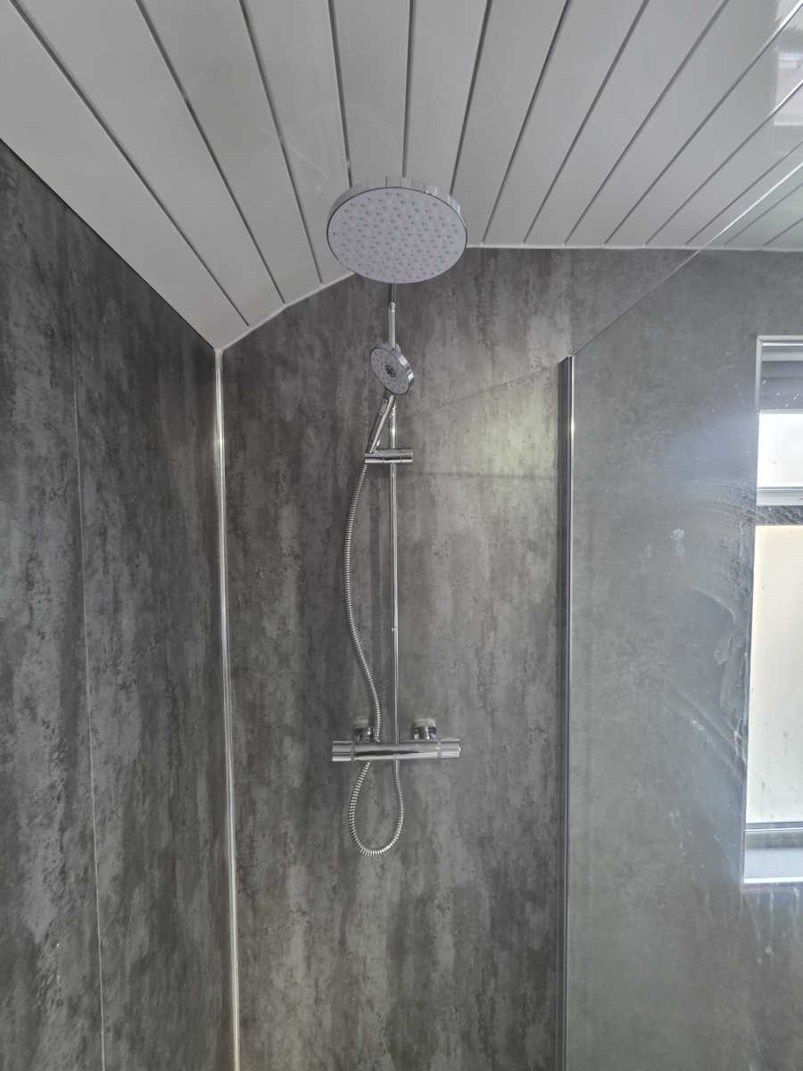 Shower enclosure with grey marble-effect wall tiles and white trim.