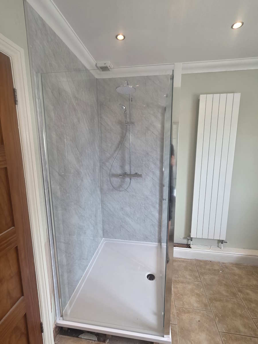 Walk-in shower with glass enclosure and contemporary wall tiling.