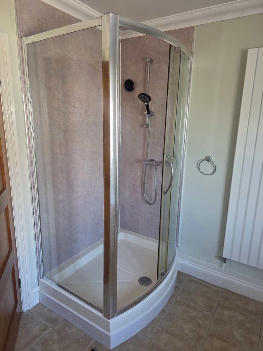 Shower enclosure with polished chrome taps and shower head fittings.