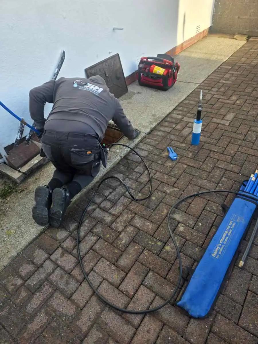 Stephen clearing debris from an outside drain in Carlisle.