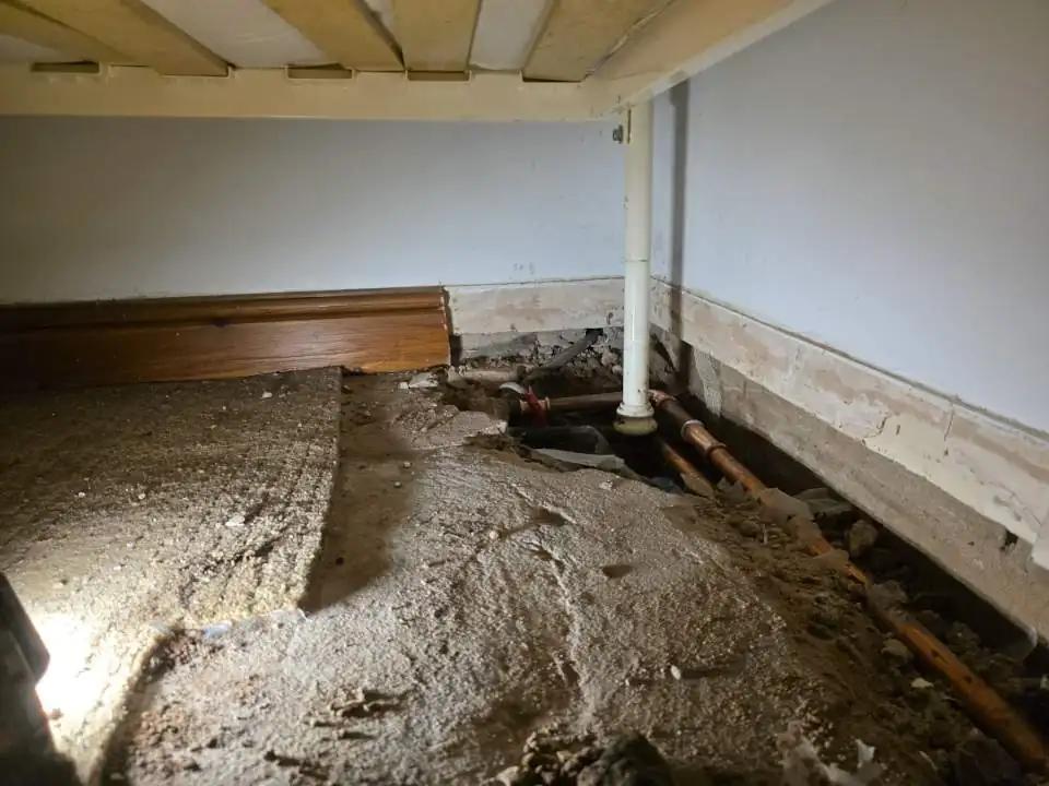 Copper pipes exposed under a bedroom floor during repair work in Carlisle.
